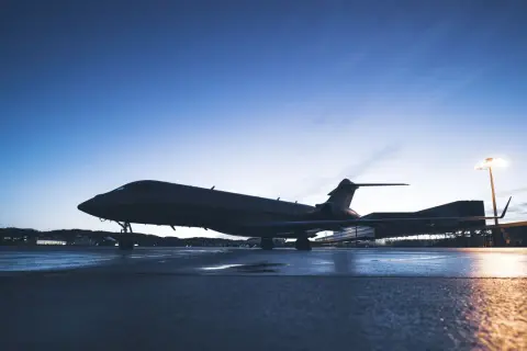 Ein Privatjet steht auf einem nassen Rollfeld bei Dämmerung.