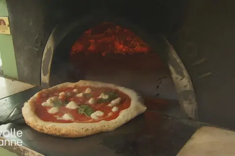 Eine authentische Pizza Napoletana mit Mozzarella und Basilikum wird in einem Holzofen gebacken.
