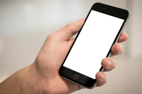 Dłoń trzyma smartfon z pustym ekranem. Chcesz wiedzieć, jak sprawdzić telefon?