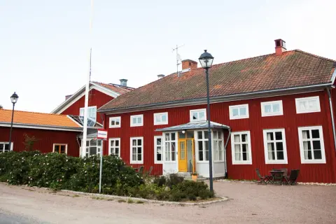 Rött stenhus med orange tak, ett stf vandrarhem med en gul dörr och en flaggstång.