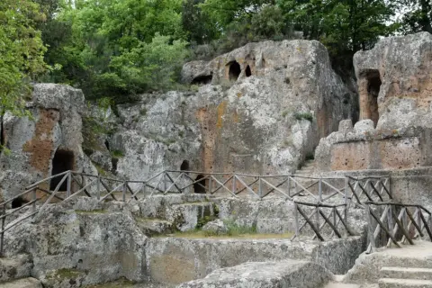 Antiche tombe etrusche scavate nella roccia, con sentieri e recinzioni in legno. Un suggestivo scorcio della mappa dei siti etruschi in Toscana.
