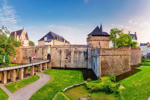 Le majestueux **Château de Nantes** se dresse fièrement, entouré de douves verdoyantes et d'une pelouse impeccable. Un pont mène à son entrée fortifiée.
