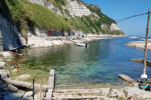 La spiaggia della Scalaccia, con le sue acque cristalline e le scogliere bianche, accoglie bagnanti e piccole imbarcazioni.
