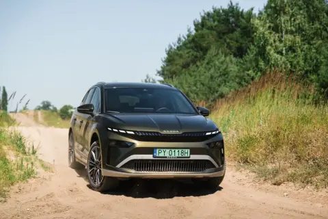 Zielona Skoda Enyaq na piaszczystej drodze, testowana pod kątem zasięgu.