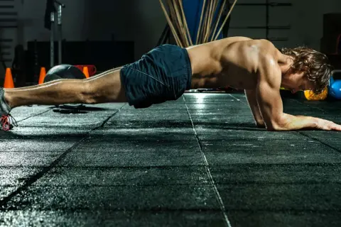 Mann im Fitnessstudio in Plank-Position, trainiert seinen Rumpf.
