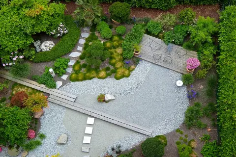 Ein moderner japanischer Garten mit Kiesflächen, Holzstegen und üppiger Bepflanzung. Tolle Garten Ideen für eine Oase der Ruhe.