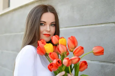 Uśmiechnięta dziewczyna z bukietem pomarańczowych i żółtych tulipanów, idealny prezent na imieniny Anity.