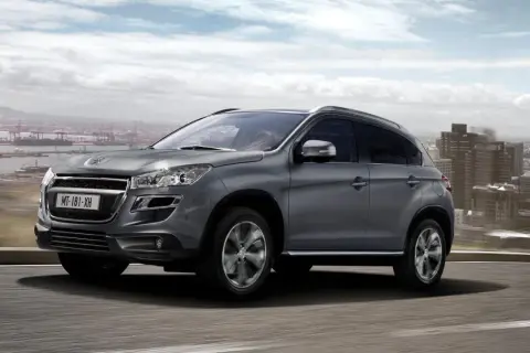 Szary Peugeot 4008 jedzie po drodze z widokiem na miasto i port.