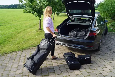 Frau packt Gepäck für den Roadtrip. Koffer und Taschen werden in den Kofferraum geladen.
