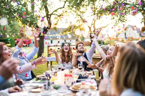 Fröhliche Gäste werfen Konfetti bei einer Gartenparty. Tolle **Gartenparty Ideen** für unvergessliche Momente mit Freunden und Familie.