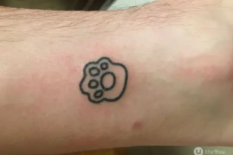 Małe tatuaże męskie: czarna łapka zwierzęcia na skórze, symbol przyjaźni i lojalności.