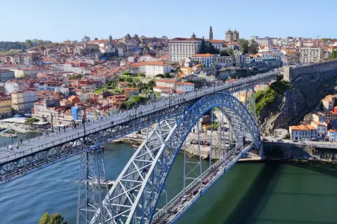Most Louisa Martinez wino, widok na most Ponte de Dom Luís I w Porto, Portugalia, z zabytkową zabudową w tle.