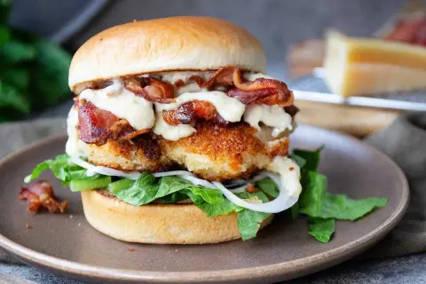 En saftig kycklingburgare med krispigt bacon, sallad, lök och en krämig dressing. Perfekt för ett gott hamburgerdressing recept.