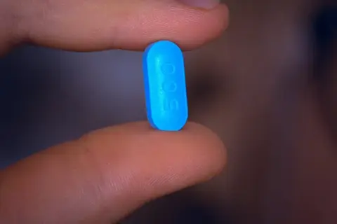 En blå tablett med siffran 500 hålls mellan fingrarna, en påminnelse om att motverka diarré vid penicillin.