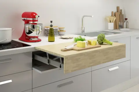 Un piano estraibile sul tavolo della cucina con formaggio, broccoli e un coltello su un tagliere.