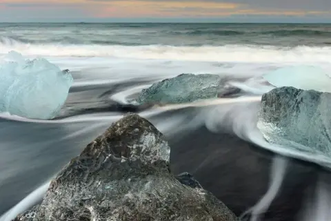 Glace sur sable noir, l'eau file en rubans soyeux grâce à la pose longue. Des diamants de glace flottent sur la plage islandaise.