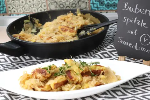 Schupfnudeln mit Sauerkraut, frisch aus der Pfanne auf einem Teller garniert mit Kräutern. Ein deftiges Gericht, das Appetit macht.
