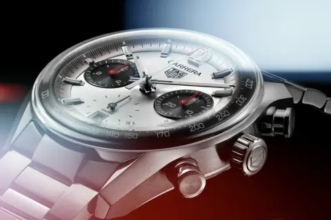 Primer plano de un reloj TAG Heuer Carrera. El cristal mineral se raya levemente, mostrando la esfera plateada y los sub-diales negros.