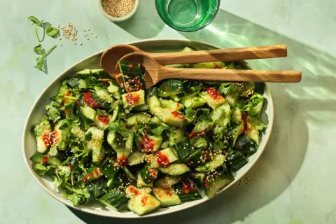 Erfrischender smashed Gurkensalat mit Koriander, Sesam und einer würzigen Sauce. Perfekt als Beilage oder leichter Snack.