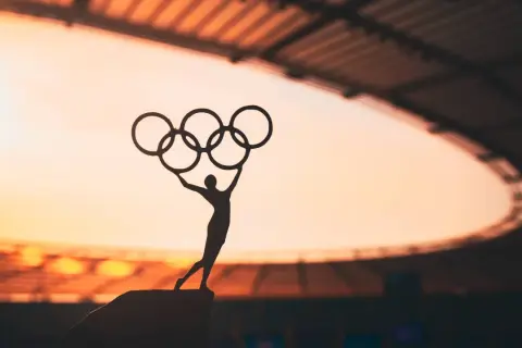 Sylwetka sportowca z pięcioma pierścieniami symbolizuje pierwsze igrzyska olimpijskie.
