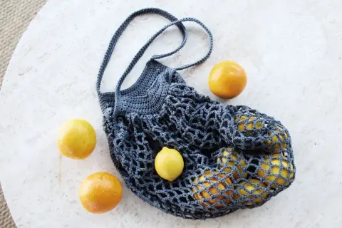 Borsa a rete uncinetto facile, perfetta per la spesa. Contiene limoni e arance, pronta per un picnic.