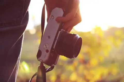 Dłoń trzyma aparat fotograficzny. Warto pomyśleć o ubezpieczeniu aparatu fotograficznego, by chronić swój sprzęt.