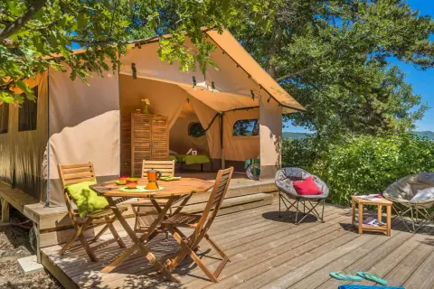 Tente aménagée pour un séjour insolite dans la Drôme, avec terrasse en bois, mobilier de jardin et vue sur la nature.