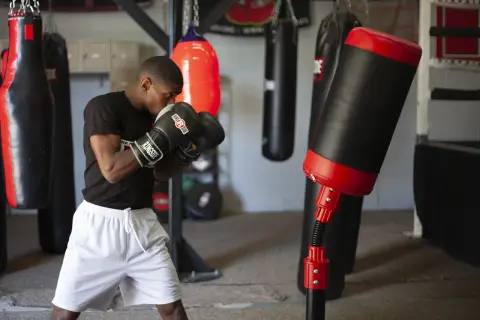 A boxer practices boxing drills in a gym, surrounded by various punching bags.
