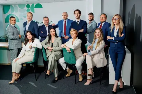 Grupa profesjonalistów w garniturach pozuje do zdjęcia w nowoczesnym biurze.