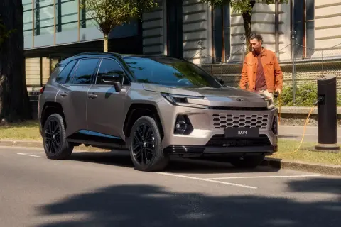 Nowy Toyota RAV4 2025 cena: stylowy SUV ładowany przy miejskiej stacji.