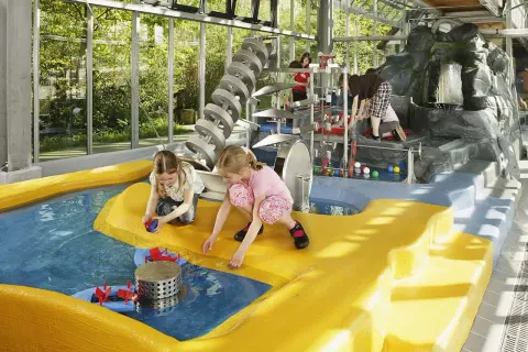Kinder spielen im Wasserbereich des vier Jahreszeiten Parks Oelde mit bunten Bällen und Wasserrädern.