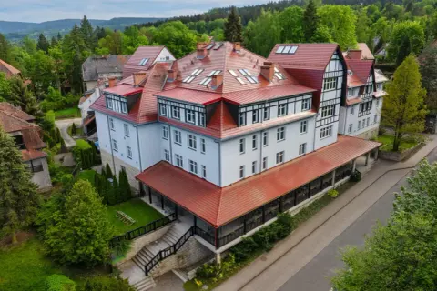 Polanica Zdrój Medical Sensus – okazały budynek z czerwoną, wielospadową dachem, otoczony zielenią.