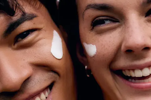 Coppia sorridente con crema sul viso, godendo dei benefici del vapore viso per una pelle radiosa.