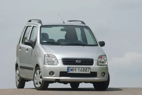 Srebrny Suzuki Wagon R+ z polskimi tablicami rejestracyjnymi WH 16887, zaparkowany na tle jasnego nieba.