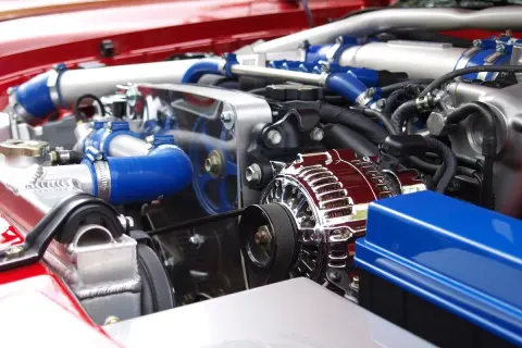 Błyszczący, chromowany alternator w nowym silniku, gotowym do mycia na sucho. Widać niebieskie przewody i elementy chłodnicy.