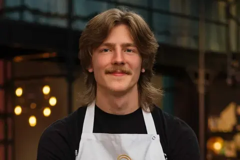 Jacob Jansson, en ung man med mustasch och långt hår, bär en vit kockförkläde.