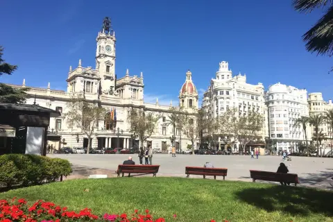 Słoneczny dzień na placu w walencja stare miasto. Ludzie odpoczywają na ławkach, podziwiając zabytkową architekturę.