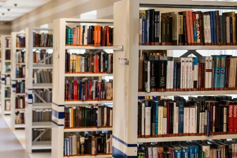 Rzędy regałów z książkami w bibliotece. Wśród nich można znaleźć pozycje dotyczące historii, w tym język chorwacki.
