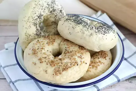 Färska bagels med vallmofrön och sesamfrön i en skål, redo för ett gott bagels recept.