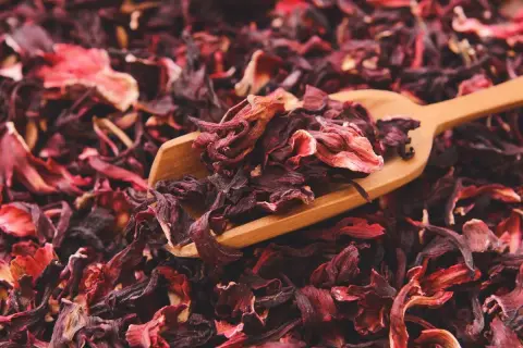 Suszone płatki hibiskusa na drewnianej łyżce. To właśnie co to jest hibiskus - piękna, czerwona roślina.