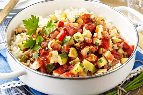 Eine köstliche zucchini-reis-pfanne einfach zubereitet mit viel Gemüse und Hähnchen. Frisch garniert mit Petersilie.