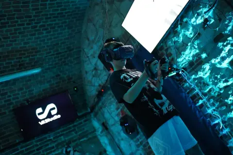 Chłopak w goglach VR w Krakowie, zanurzony w wirtualnej rzeczywistości. Na ekranie logo VRStudio.