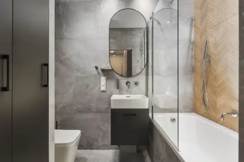 Nowoczesne **kolory do łazienki małej**: szarości, drewno i czerń tworzą elegancką, minimalistyczną przestrzeń z wanną i umywalką.