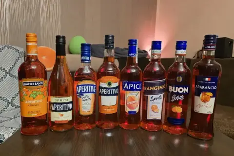 Rząd butelek z pomarańczowym aperitifem, w tym Aperol. Idealne na letnie wieczory.