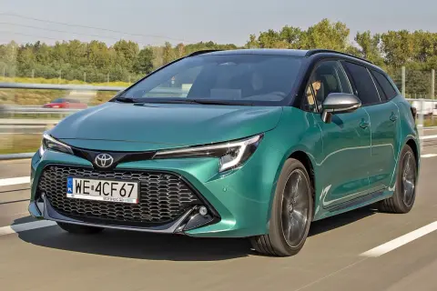 Zielona Toyota Corolla kombi jedzie po drodze, za nią widać drzewa i inny samochód.