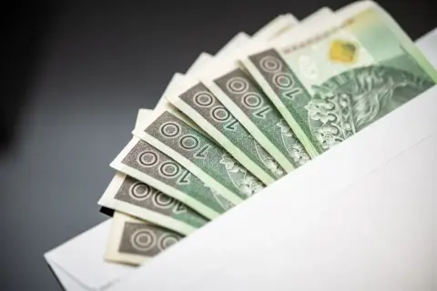 Banknoty 100 zł w kopercie. Symbol jawności wynagrodzeń i transparentności finansowej.