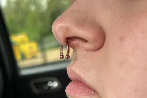 Metalowy kolczyk w nosie, w tym w przegrodzie nosowej (septum), z dwoma kulkami. Wygląda na to, że jest to idealne miejsce na taki dodatek, czyli sweet spot septum.