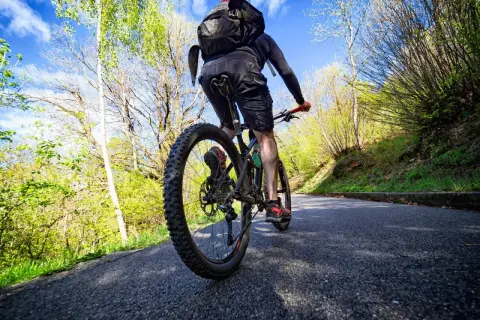 Rowerzysta na ścieżce rowerowej w Białymstoku, otoczony zielenią i błękitnym niebem.