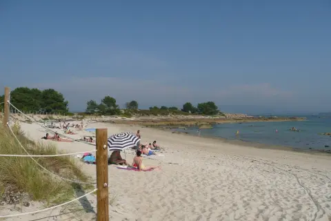 Gente disfrutando del sol en unas tranquilas playas nudistas Galicia, con arena dorada y aguas cristalinas.