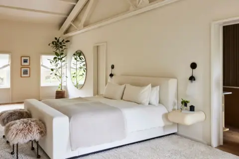 Serene bedroom with a large bed, fluffy stools, and a plant, creating positive energy placement feng shui bedroom vibes.